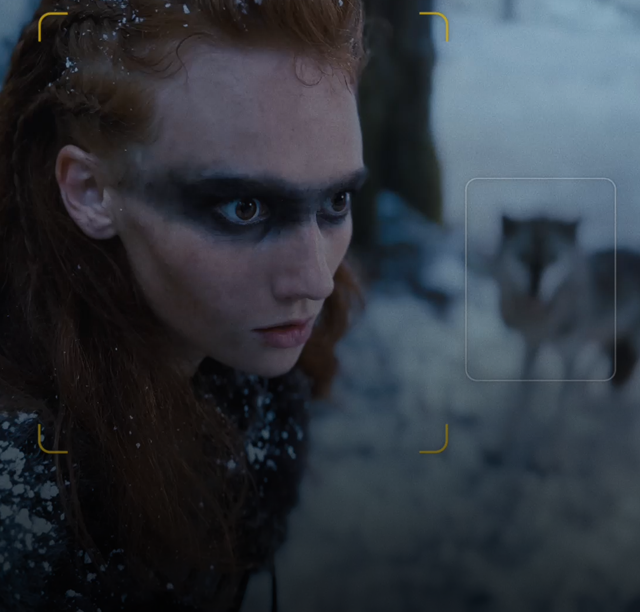 Snímek z videa ve filmařském režimu, kde je jeden člověk zaostřený v popředí a dva subjekty jsou vidět v pozadí.