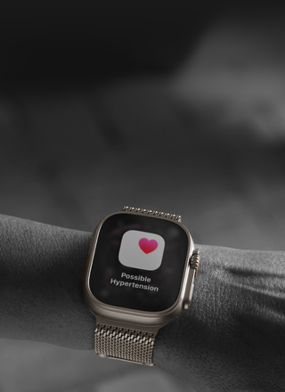 Osoba s Apple Watch Ultra 3 na zápěstí, obrazovka se zdravotním upozorněním na možnou hypertenzi