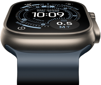 Apple Watch Ultra 3 nakloněné dopředu, pouzdro z přírodního titanu, kompas na ciferníku Orientační běh, ocelově modrý Oceánský řemínek